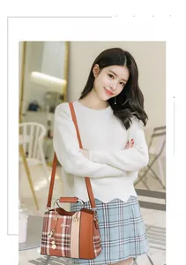 Detail of orange plaid patchwork crossbody bag with metallic circular handle and PU leather