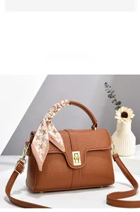 Detailed shot of brown litchi leather handbag featuring a gold buckle and houndstooth scarf