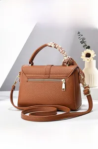 Detail view of brown pebbled leather handbag with silk scarf handle and golden hardware