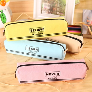 Quatre trousses en toile colorées avec fermeture éclair et citations sur une table en bois