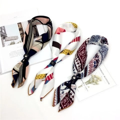 Primo piano di tre foulard di seta a motivi geometrici e paisley con fibbie ad anello
