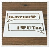 Close-up of stencil with I Love You and I Love You Too cutout designs on wood surface