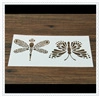 Detail showing white coffee stencils with intricate dragonfly and butterfly cutouts