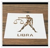 Detail of a white square Libra zodiac stencil for coffee latte art on a wooden surface