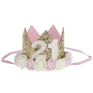Close-up of golden glitter crown with number 21 and pink white artificial roses