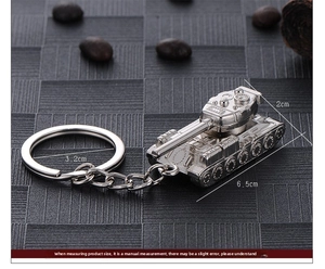 Detail of silver alloy tank model keychain with dimensions shown on a gray textured background