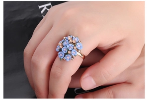 Close-up of golden adjustable ring featuring delicate light blue floral clusters and crystals