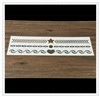 Detail of white plastic coffee stencil with star and heart patterns on wood surface