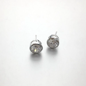 Detailed view of sterling silver stud earrings featuring round bezel-set clear zircon stones