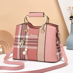 Pink checkered crossbody bag with gold metal handle and logo in minimalist setting