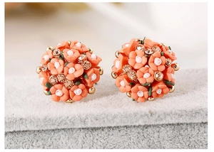 Close-up of orange floral earrings with white flowers and sparkling crystals on felt