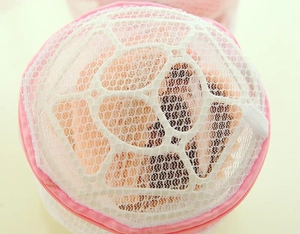 Detail of white mesh laundry bag with pink zipper and reinforced polyester stitching