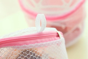 Macro detail of the reinforced mesh stitching and pink hanging loop on the laundry bag