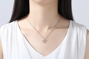 Close-up of interlocking silver heart pendant necklace with shimmering zircon details