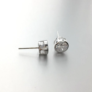 Macro detail of 925 sterling silver stud earrings with clear round bezel-set zircon