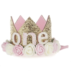 Close-up of glittery gold baby birthday crown with pink foam roses and 'one' lettering