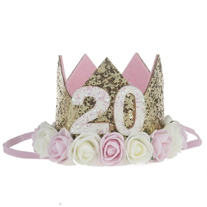 Close-up of golden glitter birthday crown with number 20 and pink rose details