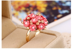 Detailed close-up of golden ring with pink flowers and crystals in a beige velvet box