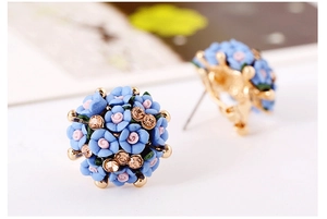 Detailed close-up of rose floral earrings with blue ceramic petals and gold crystal centers