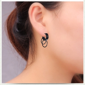 Close-up of black surgical steel hoop earring with triple ring charms on ear