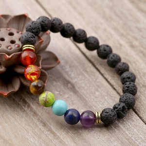 Lava stone chakra bracelet with rainbow beads on a natural wooden background