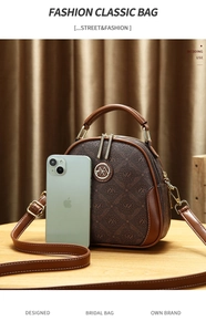 Close-up of vintage brown pattern handbag featuring round metal logo and dual zipper detail