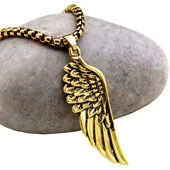 Detailed view of a gold wing pendant necklace resting on a smooth decorative stone