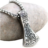 Detailed view of a silver stainless steel viking axe pendant on a smooth grey pebble