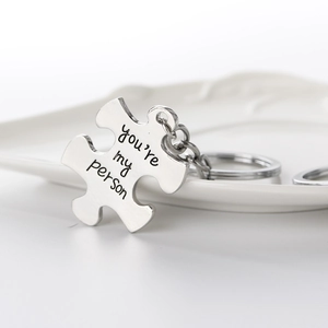 Detailed macro view of puzzle-shaped metal keychain with you're my person engraving
