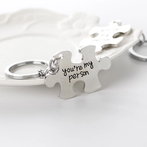 Close-up of puzzle piece keychains engraved with You're My Person text on a white tray