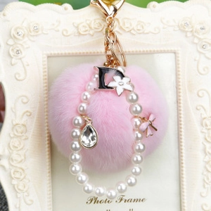 Détail d'un porte-clés rose en peluche avec anneau de perles et breloques de fleurs