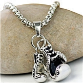 Detailed close-up of silver boxing glove pendant on a rugged box chain over a pebble