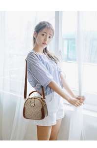 Close-up of vintage monogram crossbody bag with round metal logo and dual zippers