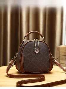 Detailed close-up of a brown monogram shell bag with golden logo on a light wood surface