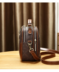 Detail view of the brown monogram crossbody bag with dual zippers and gold hardware