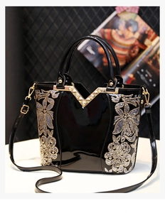Vue détaillée du sac en cuir verni noir avec broderie florale dorée et rivets décoratifs
