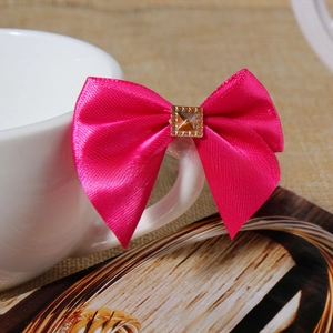 Close-up of pink satin bow with golden champagne rhinestone on a ceramic cup handle