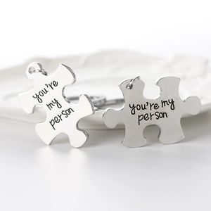 Macro shot of silver puzzle piece keychains engraved with You're My Person for couples