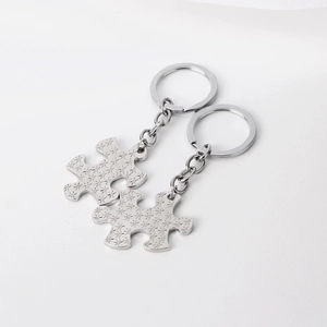 Detailed view of two silver jigsaw puzzle keychains with etched star patterns and metallic shine