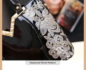 Détail du sac à main en cuir verni noir avec broderies florales en paillettes dorées
