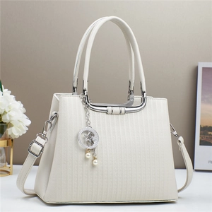 White structured handbag with vertical stripes and star pearl charm on a stylish table