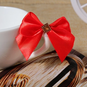 Close-up of red satin ribbon bow with a brown square rhinestone on a white cup