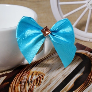 Detail of sky blue satin ribbon bow with center brown rhinestone on ceramic cup