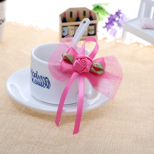 Detailed pink handmade bow with satin rose and mesh accents on a white coffee cup