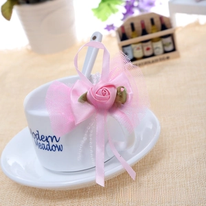 Detail of pink handmade crochet bow with silk rose and pearls decorating a cup handle