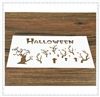 Detail view of a white Halloween stencil with cut-out letters and dead tree silhouettes