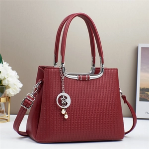 Detail view of burgundy tote bag with star-moon pendant and vertical embossed patterns