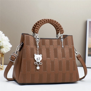 Close-up of deep brown crossbody bag featuring textured patchwork and a bear charm pendant