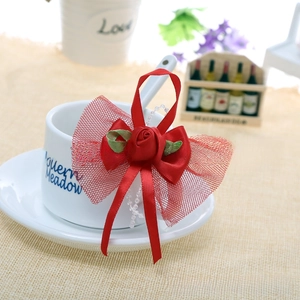 Close-up of handmade red ribbon bow with fabric rose and white pearl chain detail
