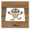 Detail view of a white stencil with a cartoon monster cutout on a wooden surface